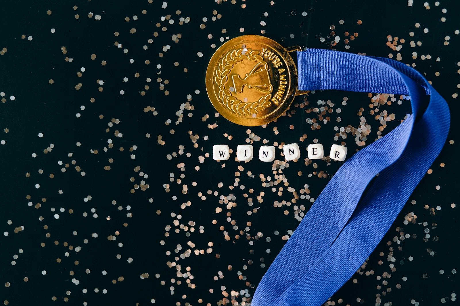 Close-Up Shot of a Gold Medal on a Black Surface