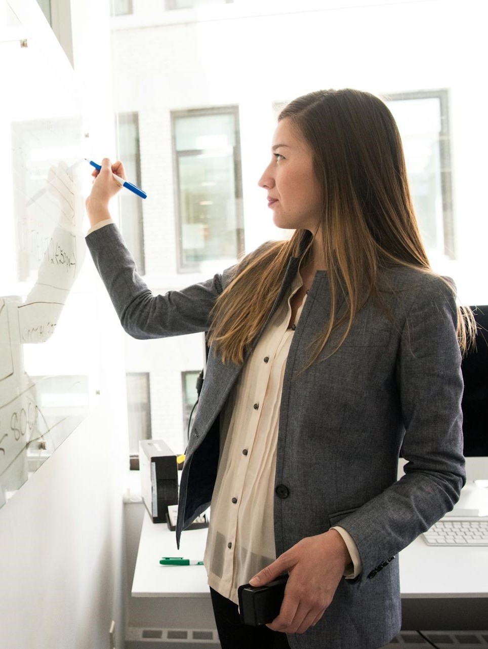 Woman Wearing Gray Blazer Writing on Dry-erase Board